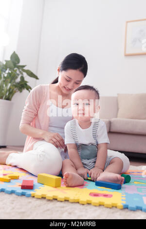 La madre gioca con il baby sitting room Foto Stock