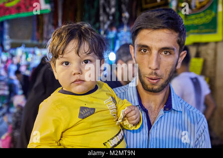 Tehran, Iran - 27 Aprile 2017:iraniano che con il suo figlio nelle sue braccia si erge nel mercato. Foto Stock