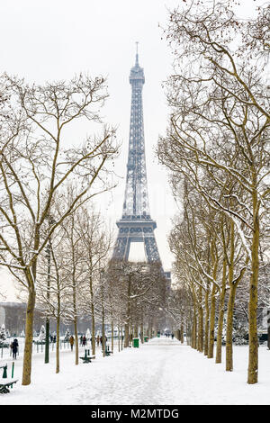 Inverno a Parigi nella neve. La torre Eiffel si vede dal Champ de Mars con una coperta di neve alberata vicolo in primo piano. Foto Stock
