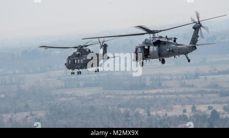 Un HH-60G Pave Hawk elicottero assegnato alla cinquantaseiesima Rescue Squadron vola con un italiano HH-101A Cesare vicino la base aerea di Aviano, Italia, durante una routine di formazione missionaria a gennaio 26, 2018. Membri provenienti da la 56th e la 57th RQS sono battenti in tutta la regione durante diverse incursioni di formazione. La loro presenza all'interno dell'area aumenterà man mano che iniziano per la transizione dalla Royal Air Force Base Lakenheath, Inghilterra. Circa 350 personale, cinque HH-60G Pave Hawk elicotteri sono attesi a trasferirsi a Aviano AB nel tentativo di stabilire il permanere di un personale percorso di recupero all'interno dell'Europa. (U.S. Aria F Foto Stock