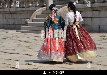 Due giovani donne che indossano abiti tradizionali a piedi attraverso Piazza - presso il Palazzo Gyeongbokgung, Seoul, Corea del Sud 3 Aprile 2017 Foto Stock