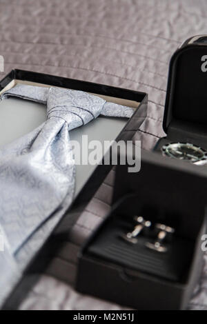 Elegante festa nuziale matrimonio uomo Cravatta fatta di seta delicato materiale tessile con un oriental modello geometrico nella casella su grigio coverlet vicino a st Foto Stock