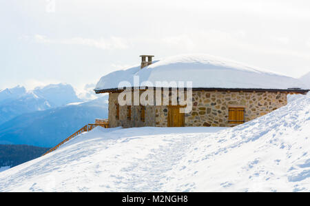 Vista panoramica di idilliaci winter wonderland con cime e tradizionali chalet di montagna nelle Dolomiti nella luce del tramonto Foto Stock