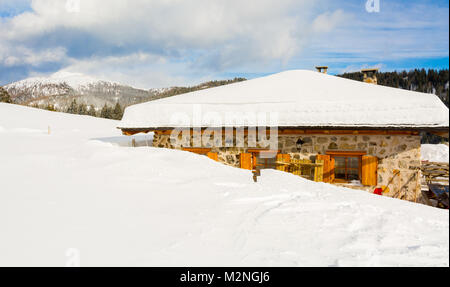 Vista panoramica di idilliaci winter wonderland con cime e tradizionali chalet di montagna nelle Dolomiti nella luce del tramonto Foto Stock