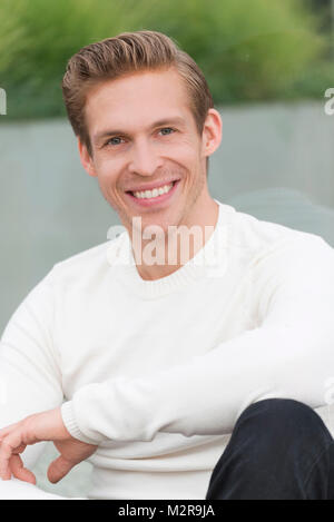Giovane uomo al di fuori, sorriso, ritratto Foto Stock
