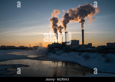 Un impianto per garantire il riscaldamento per il popolo di Yakutsk in Siberia rilascia fumo nell'aria come tramonto. Yakutsk è la seconda più fredda in grandi città Foto Stock