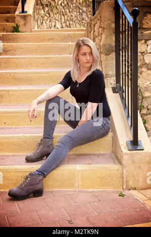 Bella ragazza bionda che indossa jeans stretti e una t-shirt nera all'aperto Foto Stock