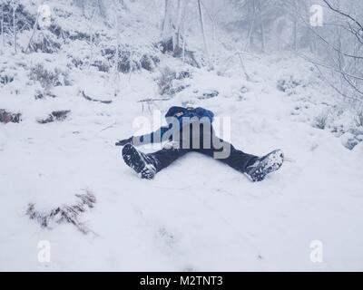 Ragazzo divertente posa in neve e rende un angelo con diffusione di armi. Kid giochi nella neve fresca su terreni sassosi hill. Foto Stock