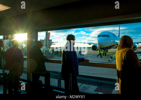 I passeggeri in attesa di salire a bordo di un volo Ryanair presso l'aeroporto di Bristol, sunrise causando lens flare sulla sinistra Foto Stock