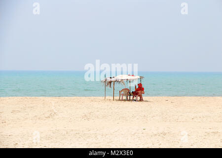 Un bagnino rosso si siede su una sedia in un resort sulla spiaggia senza turisti Foto Stock