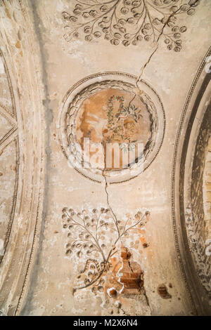 Interno dell antico borgo medioevale di stampaggio di argilla e pittura in forma di fiori in stile barocco su un fatiscente soffitto marrone con crepe e arco Foto Stock