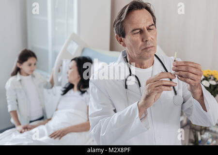 Maschio serio controllo medico siringa prima dell'iniezione Foto Stock