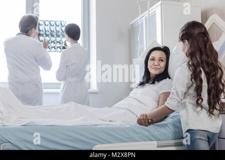 Preoccupato figlia visitando la sua mentalità positiva la mamma in ospedale Foto Stock