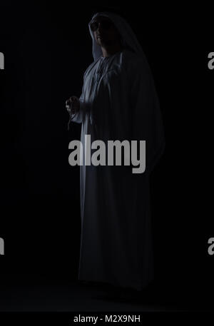Tasto basso colpo di sheik permanente con occhiali da sole di fronte a sfondo nero Foto Stock