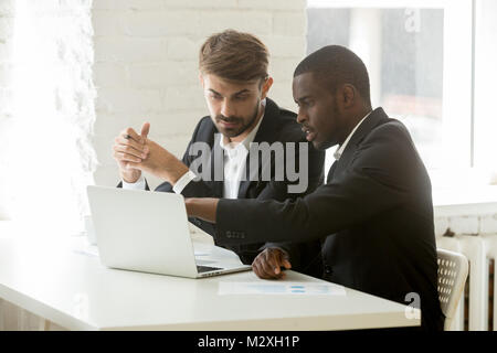 E multirazziale i partner aziendali nelle tute per discutere del progetto online Foto Stock