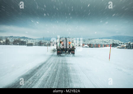 Servizio invernale carrello gritter o spandimento di sale sulla superficie della strada per impedire la formazione di ghiaccio nella neve tempestoso giorno d'inverno. Foto Stock