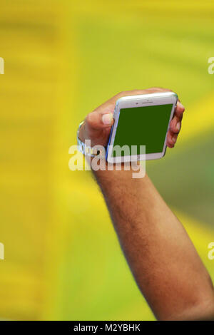 Mock up del maschio di mano azienda nero cellulare a sfondo verde. Foto Stock