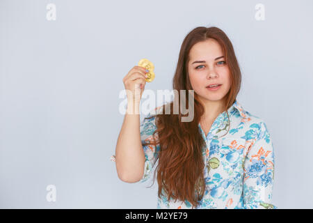 Bruna giovane donna detiene un oro bitcoin in mano Foto Stock