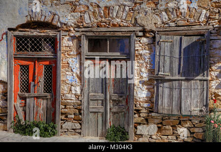 Vista frontale di weathered porte e finestra in una città abbandonata casa in Syros Island in Grecia. Foto Stock