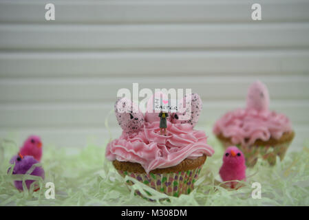 Tempo di Pasqua cupcake rosa con decorazioni di uova e la persona in miniatura statuetta sulla parte superiore con un segno di Io amo la Pasqua Foto Stock