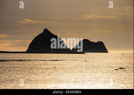 La retroilluminazione di enormi rocce nella baia di New Plymouth, Mount Taranaki, Isola del nord, Nuova Zelanda Foto Stock