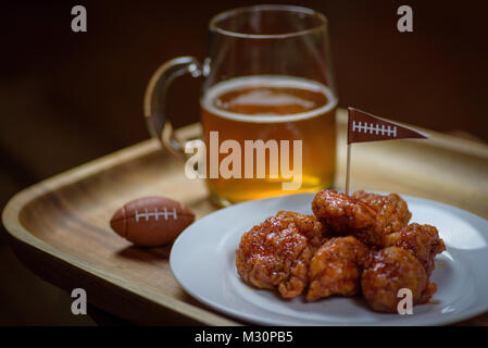 Macro close up della piastra di carni disossate ali a caldo e la tazza di vetro di birra per la grande partita di calcio Foto Stock