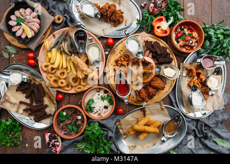 Tavolo per la cena con i gamberi, pesce alla griglia, insalate, diversi spuntini e birra chiara, vista dall'alto Foto Stock