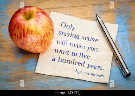 Solo rimanendo attivo vi faranno venire voglia di vivere di un centinaio di anni, proverbio giapponese - scrittura su un tovagliolo con un fresco apple Foto Stock