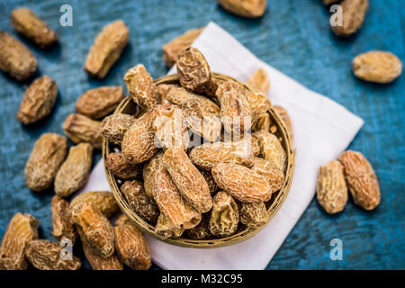 In prossimità delle materie di datteri secchi,Phoenix dactylifera in una ciotola tradizionale su una superficie di legno. Foto Stock
