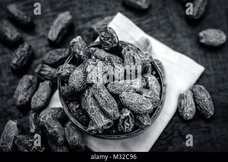 In prossimità delle materie di datteri secchi,Phoenix dactylifera in una ciotola tradizionale su una superficie di legno. Foto Stock