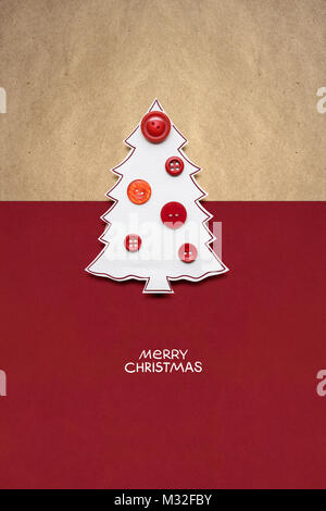 Concetto creativo foto di albero di Natale fatto di carta e pulsanti sul rosso sfondo marrone. Foto Stock