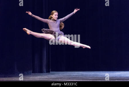 Ragazza di dodici anni sul palco di ballo facendo un cavallo di salto Foto Stock