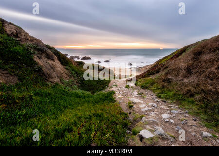 Un sentiero roccioso conduce giù alla spiaggia di Bodega testa vicino a Bodega Bay al tramonto, California. Foto Stock