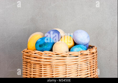 Molte colorate uova di pasqua nel cesto di vimini Foto Stock