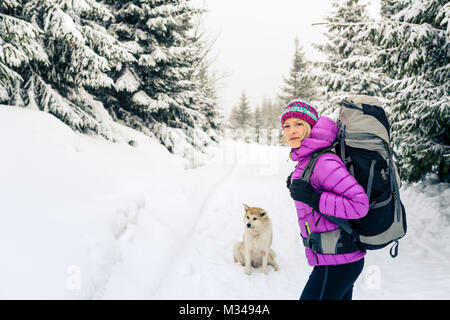 Donna escursionismo in bianco inverno boschi della Foresta con cane akita. La ricreazione del fitness e uno stile di vita sano all'aperto in natura. Motivazione e di ispirazione wi Foto Stock