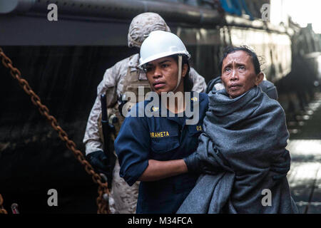 150610-M-ST621-321 Stretto di Makassar (10 giugno 2015) un marinaio prende una donna per il personale medico a bordo il dock anfibio sbarco nave USS Rushmore (LSD 47). Rushmore salvato 65 persone da un naufragio imbarcazione nell'oceano pacifico tra le isole indonesiane di Kalimantan e Sulawesi. Una volta a bordo, la salvò gli individui sono stati forniti cibo e cure mediche da marines e marinai dal XV Marine Expeditionary Unit e la Essex anfibio gruppo pronto. (U.S. Marine Corps foto di Sgt. Emmanuel Ramos/RILASCIATO) USS Rushmore Aids 65 persone in mare nei pressi di Indonesia da #PACOM Foto Stock