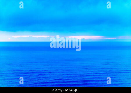 Stilizzato paesaggio astratto seascape tramonto lunga esposizione con le nuvole sotto diverse sfumature di blu, arancione, giallo e rosso Foto Stock