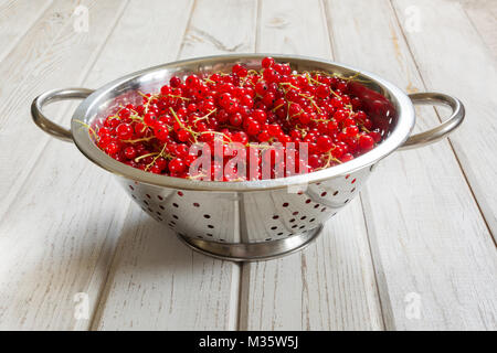 Colapasta pieno di raccolti di fresco Ribes rosso su sfondo di legno. Vista laterale. Foto Stock