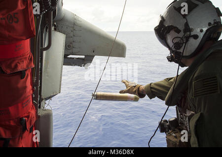 160626-N-GP548-047 Mare delle Filippine (26 giugno 2016) - Aircrewman navale (elicottero) 1a classe Justin Wright, nativo di Linden, California, distribuisce un MK25 svasatura di fumo durante un combattimento di ricerca e di salvataggio (CSAR) evoluzione della formazione a bordo di un MH-60S Sea Hawk elicottero, assegnato al "falchi d'Oro" di elicottero di mare squadrone di combattimento (HCS) 12. HSC-12 è imbarcato a bordo della USS Ronald Reagan (CVN 76) con Carrier aria Wing (CVW) 5 a sostegno della sicurezza e della stabilità in Indo-Asia-Pacifico. (U.S. Foto di Marina di Massa lo specialista di comunicazione 1a classe Elia G. Leinaar/RILASCIATO) Naval gli equipaggi di volo rimangono rea Foto Stock