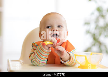 Happy baby boy in attesa di cibo con cucchiaio a tavola Foto Stock