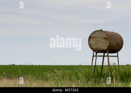 Vecchio arrugginito serbatoio acqua e canna sulle pianure sotto un aspetto lattiginoso cielo bianco Foto Stock