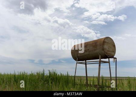 Vecchio arrugginito serbatoio acqua e canna sulle pianure sotto un aspetto lattiginoso cielo bianco Foto Stock