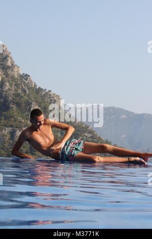 Un adolescente sconosciuto sul bordo di una piscina infinity mentre è in vacanza in Turchia Foto Stock