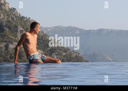 Un adolescente sconosciuto sul bordo di una piscina infinity mentre è in vacanza in Turchia Foto Stock