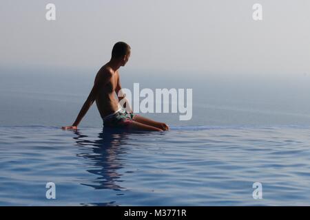 Un adolescente sconosciuto sul bordo di una piscina infinity mentre è in vacanza in Turchia Foto Stock