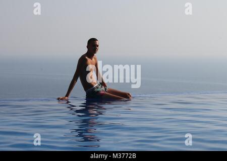 Un adolescente sconosciuto sul bordo di una piscina infinity mentre è in vacanza in Turchia Foto Stock