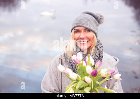 Ritratto di donna bionda di fronte lago con i tulipani Foto Stock