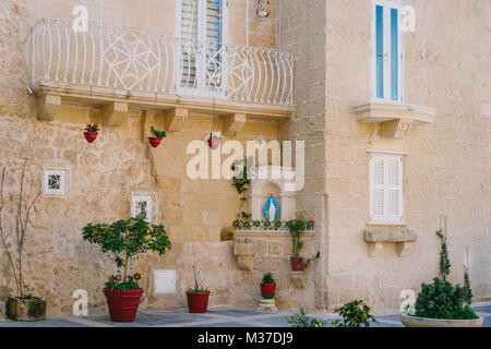 Mdina, Malta. Strada stretta della città antica con il maltese casa costruita di pietra calcarea. La casa decorata nella tradizione cattolica Foto Stock