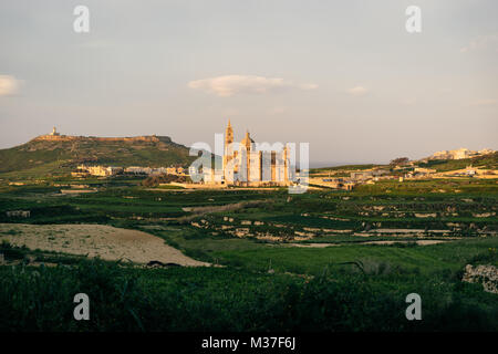 A Gozo, Malta. Nostra Signora di Ta Pinu Basilica vista dal villaggio di Gharb al tramonto Foto Stock