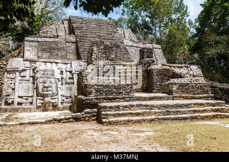 Vecchia pietra antichi Maya di civiltà precolombiane piramide con volto scolpito ed ornamento nascoste nella foresta, Lamanai sito archeologico, Orange Walk Foto Stock